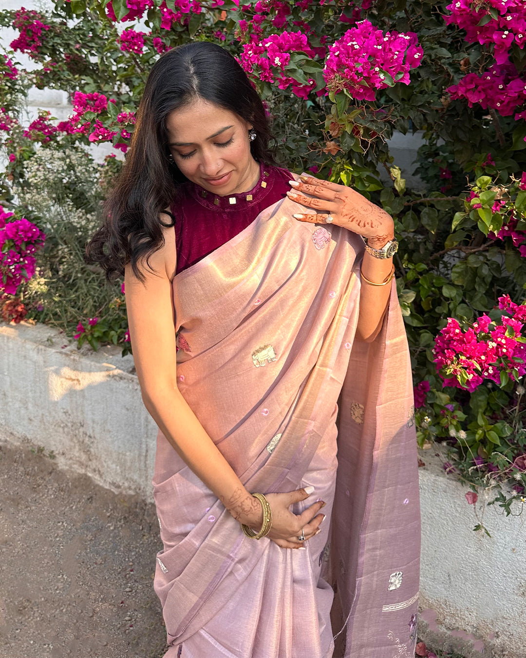 Woman in a pink saree standing in front of pink flowers
