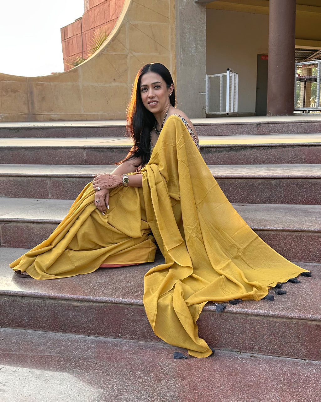 Elegant seated view of the Mustard Yellow Mul Cotton Saree by Rajathee Saree showcasing its soft and natural easy drape.