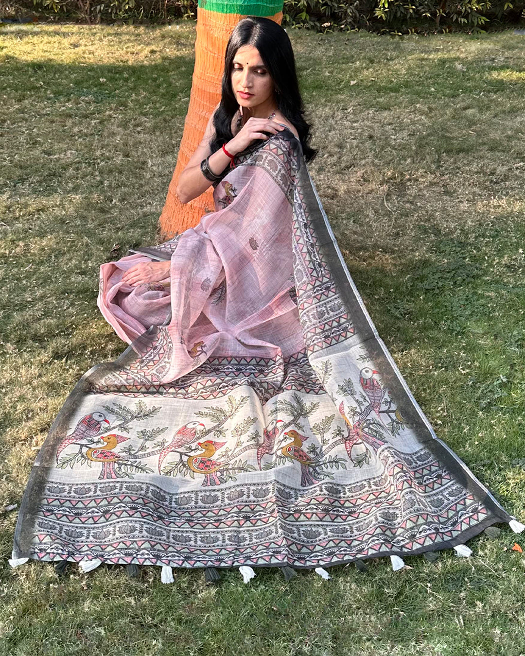 Seated view of Rajathee Saree Black and Pink Cotton Super Net showcasing the detailed peacock-inspired pallu design.