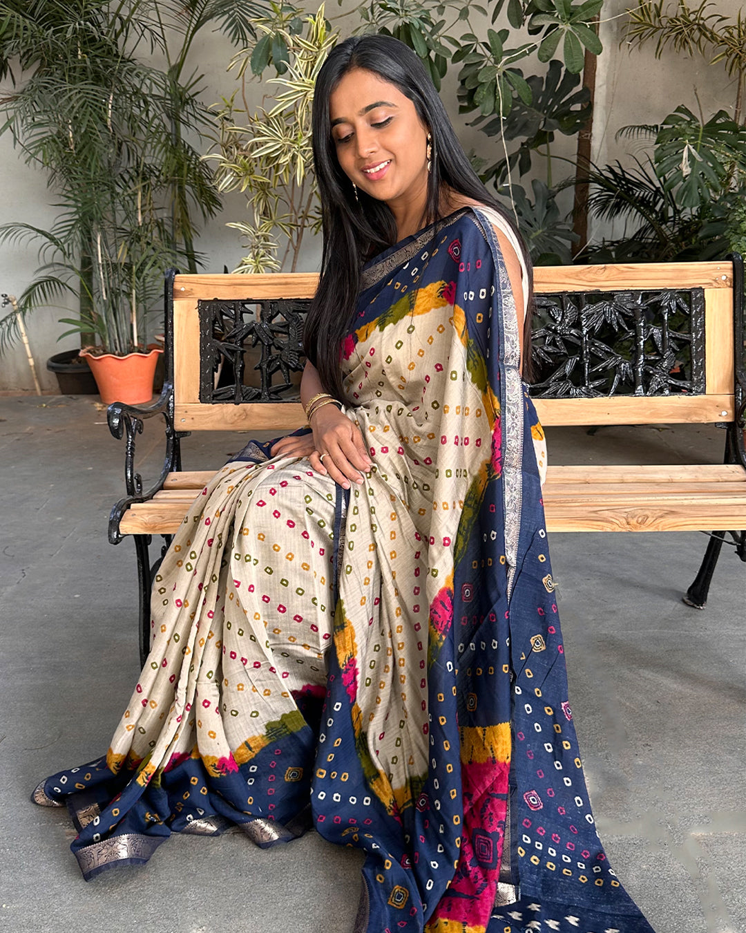 Elegant seated view of the Rajathee Saree Ivory and Blue Bandhani print saree showcasing its fluid, lightweight drape.