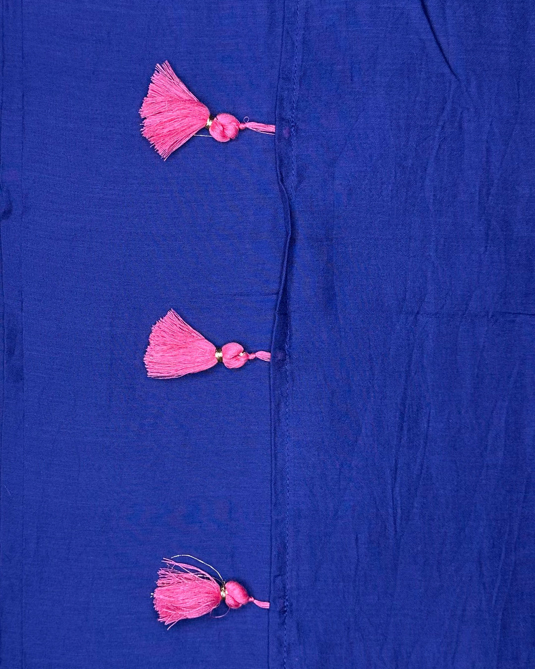 Close-up of the vibrant pink tassel accents on the border of the Deep Blue Mul Cotton Rajathee Saree.