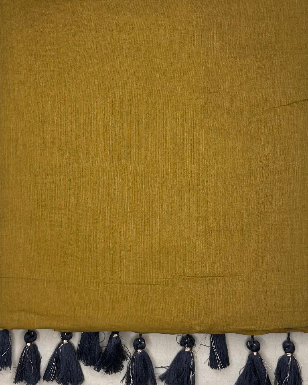 Close-up of the breathable Mustard Yellow Mul Cotton fabric and high-quality dark tassels from Rajathee Saree.