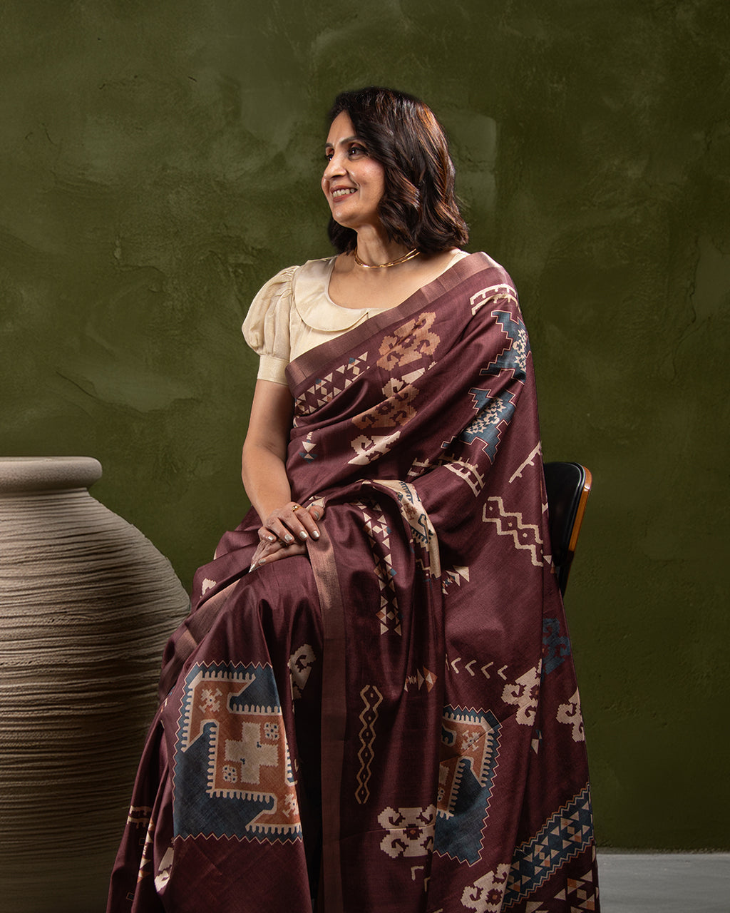 Seated view of the Brown Cotton-Tissue Saree by Rajathee Saree highlighting the soft sheen and traditional print artistry.