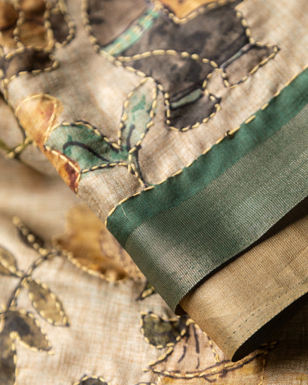 Close-up of the botanical narrative motifs and traditional artistry on the Bottle Green Rajathee Saree.