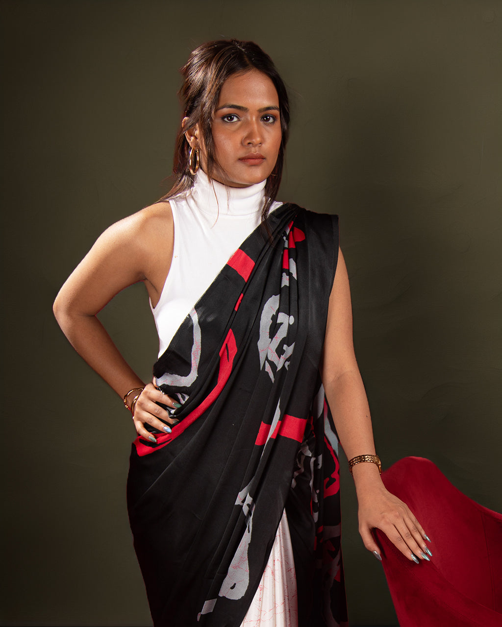 A model posing in a modern black crepe saree with a minimalist abstract print and vibrant red accents.