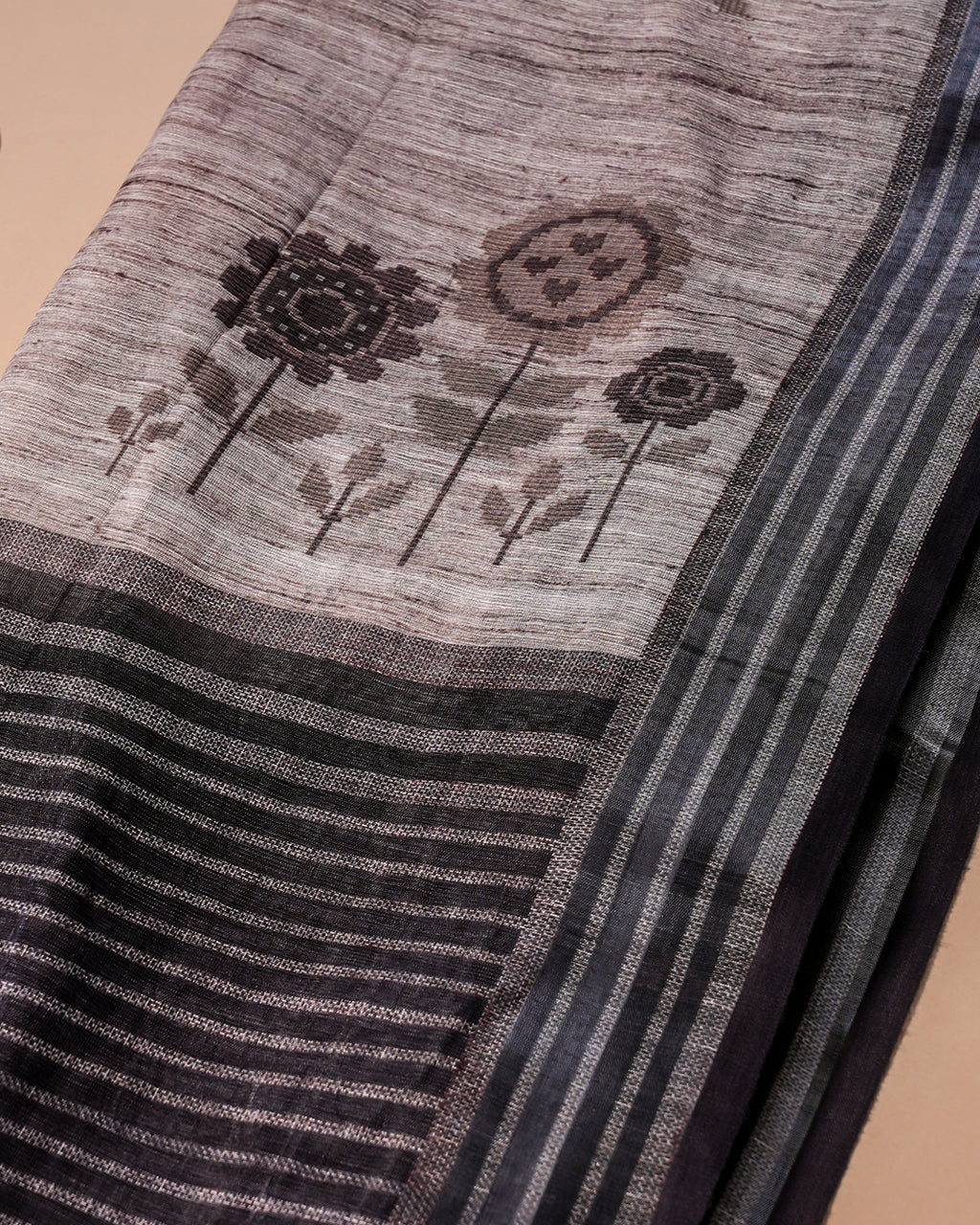 Close-up shot of the saree's pallu highlighting the minimal floral motifs and the contrasting black striped border.