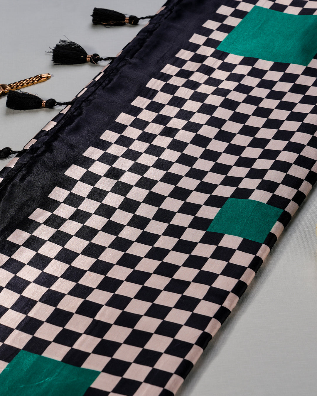 Detailed view of the vibrant emerald green pallu and coordinating black tassels on the Queen's Grid Saree.