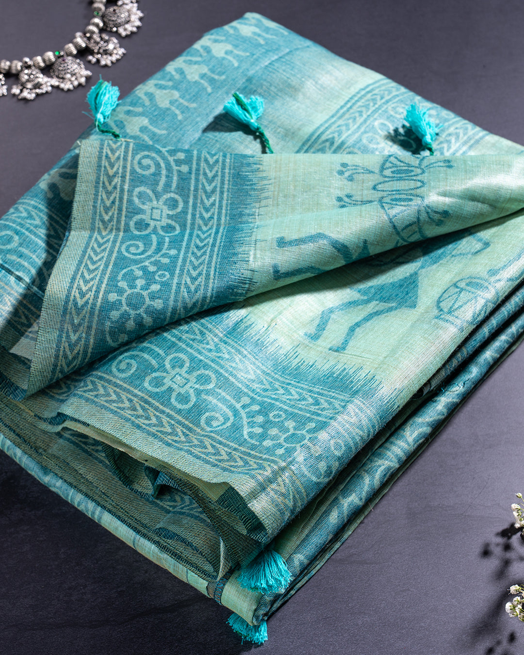 Folded Sea Green Cotton Saree by Rajathee Saree highlighting the easy-to-drape fabric and coordinating tassel accents.