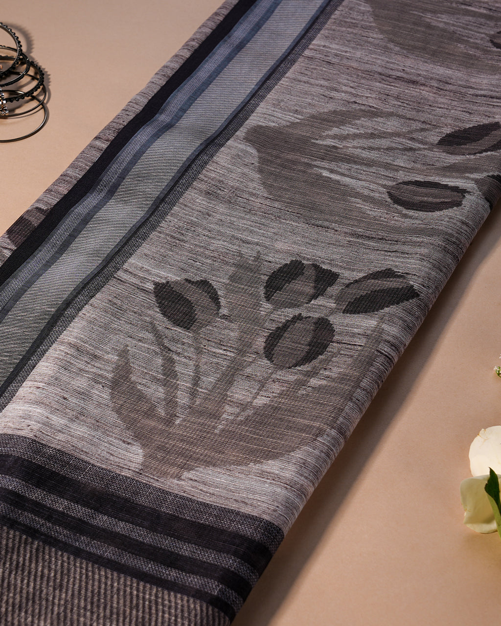 Close-up of the grey cotton fabric with large grey floral and subtle round motifs from Rajathee Saree.