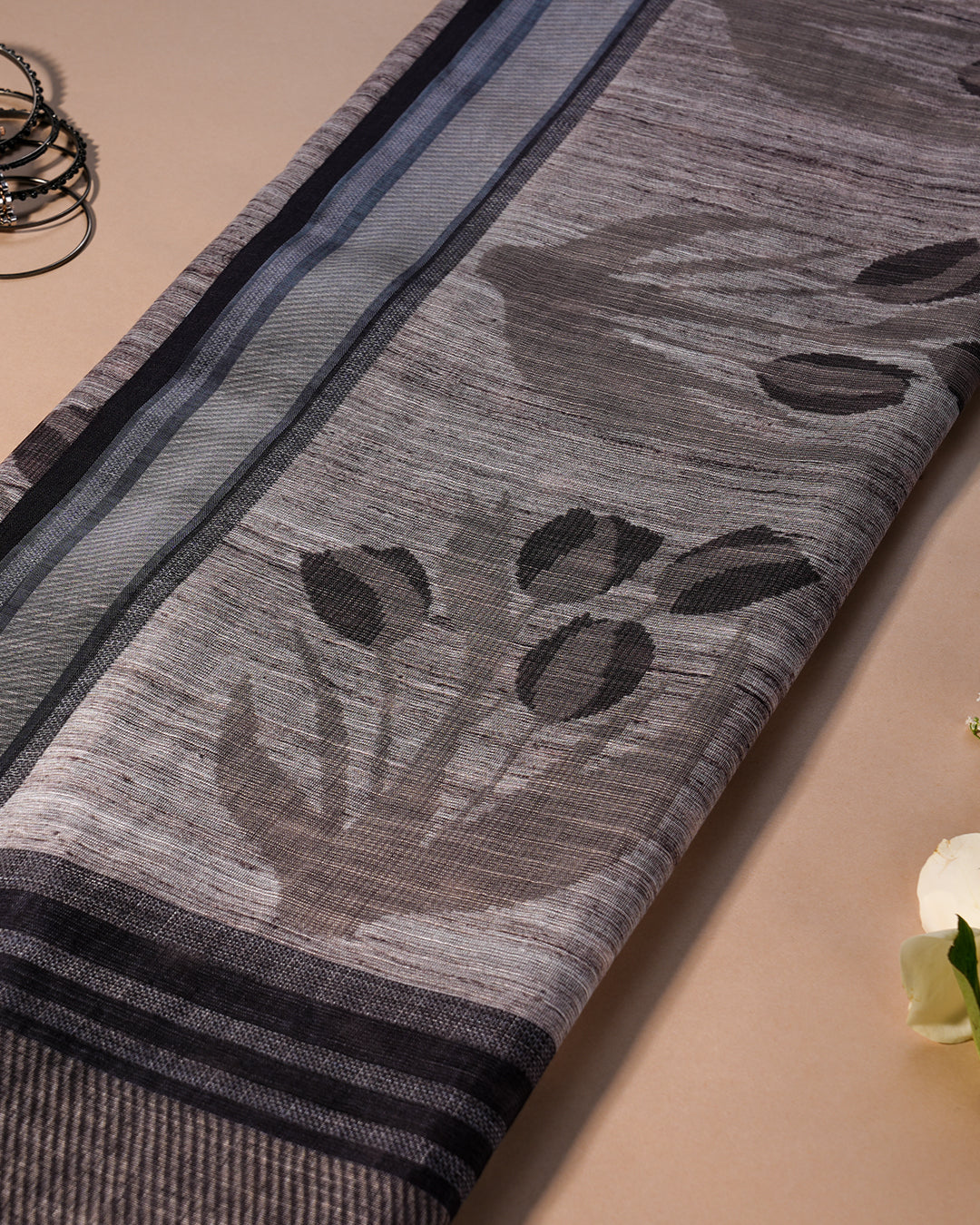 Close-up of the grey cotton fabric with large grey floral and subtle round motifs from Rajathee Saree.