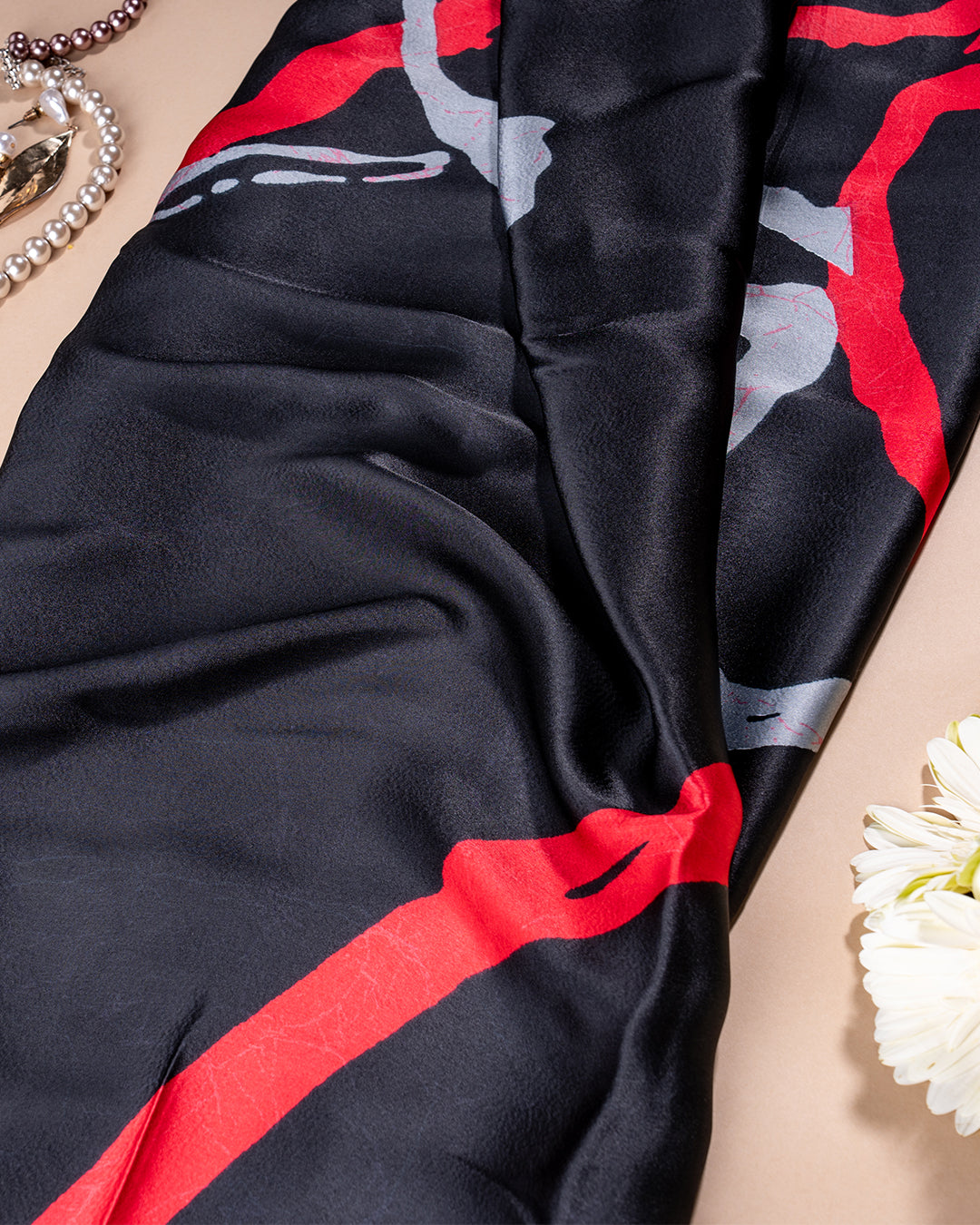 Texture shot of the black crepe saree showcasing the fine quality of the fabric and the fluid red brush stroke design.