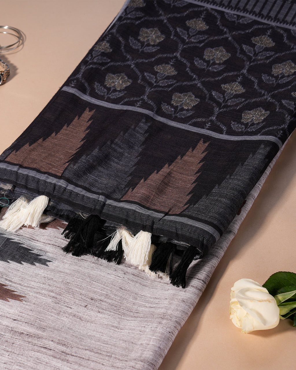 Showcase of the striped black and grey pallu with coordinating black and white tassels on the Grey Cotton Saree.