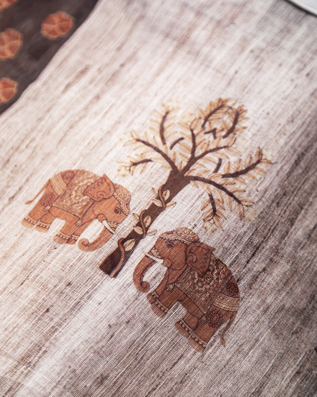 Close-up of the intricate brown elephant and tree motifs on the Grey Cotton fabric from Rajathee Saree.