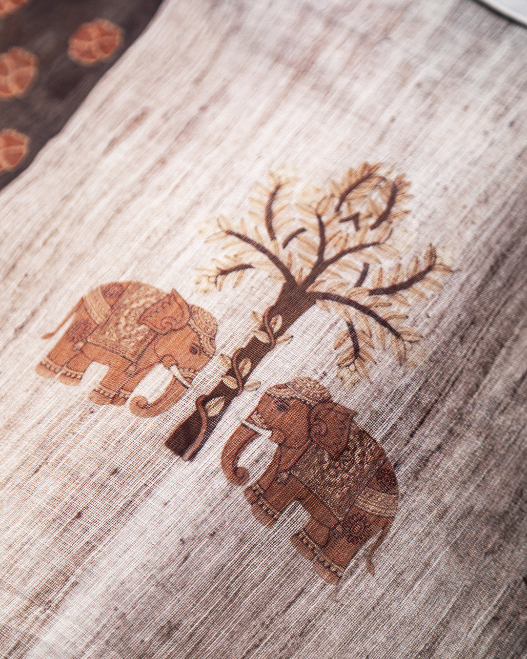 Close-up of the intricate brown elephant and tree motifs on the Grey Cotton fabric from Rajathee Saree.