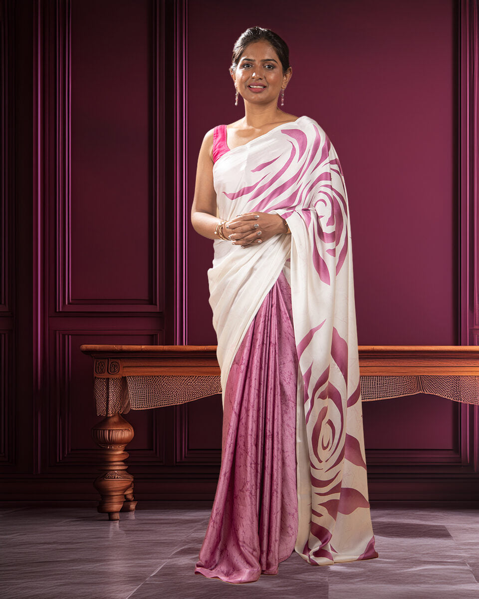 A model elegantly draped in a smooth pink and white crepe saree featuring a scattered abstract rose flower print and a flattering, flowy silhouette.